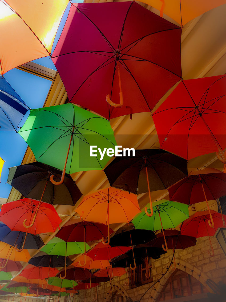 LOW ANGLE VIEW OF MULTI COLORED UMBRELLAS HANGING ON CEILING
