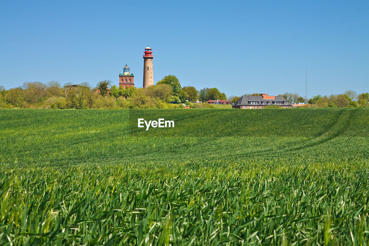 Scenic view of lighthouse on field in front of clear blue sky