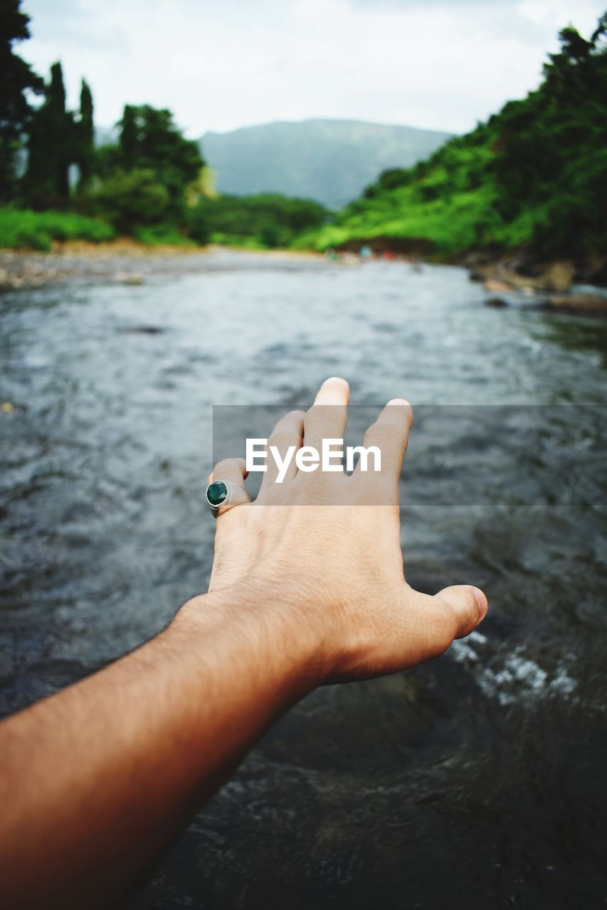 Close-up of hand gesturing over river