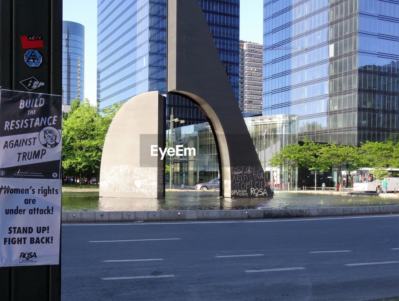 CLOSE-UP OF ROAD SIGN AGAINST MODERN BUILDINGS