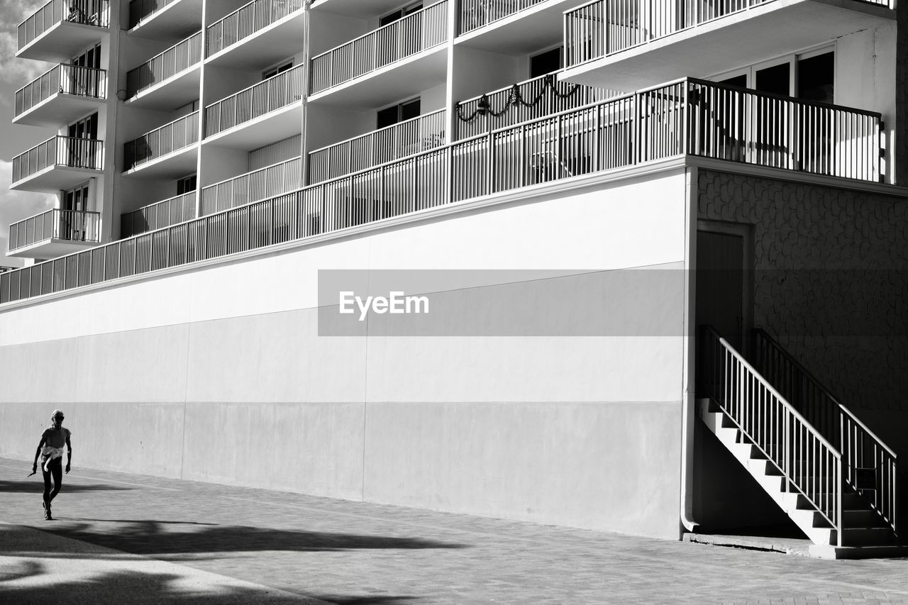 MAN WALKING BY MODERN BUILDING