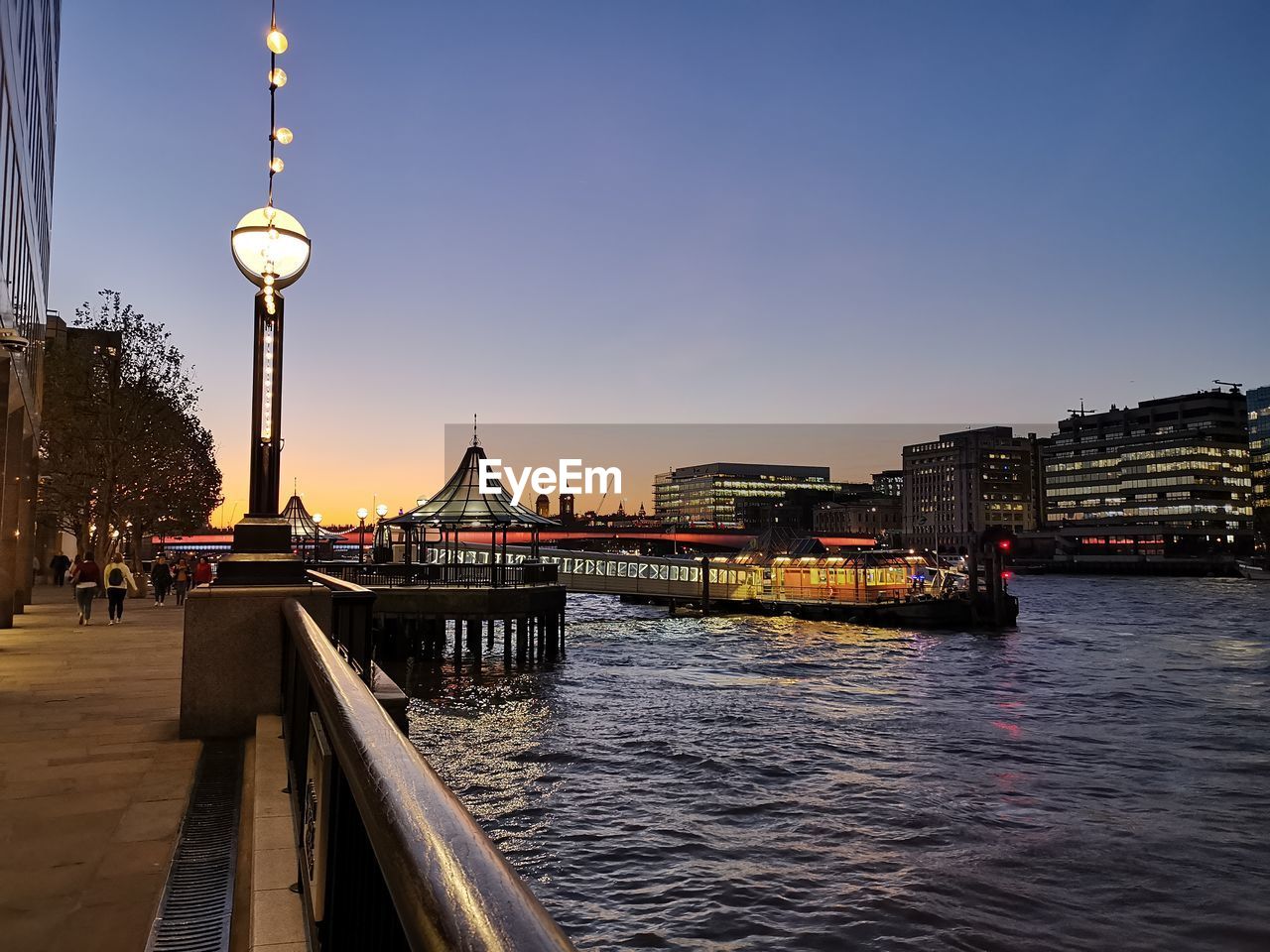 BRIDGE OVER RIVER BY BUILDINGS AGAINST SKY