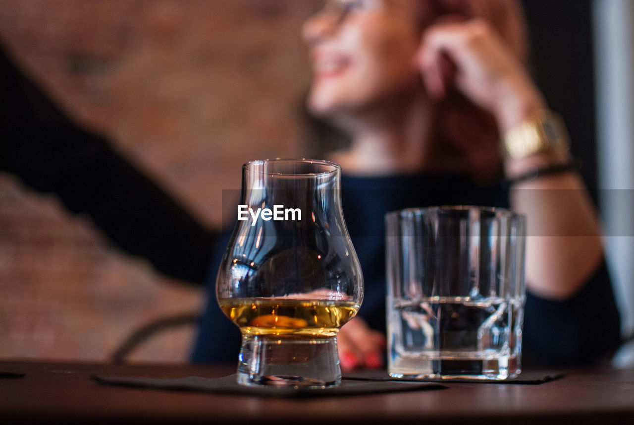 Close-up of scotch whiskey in glass with people in background at bar