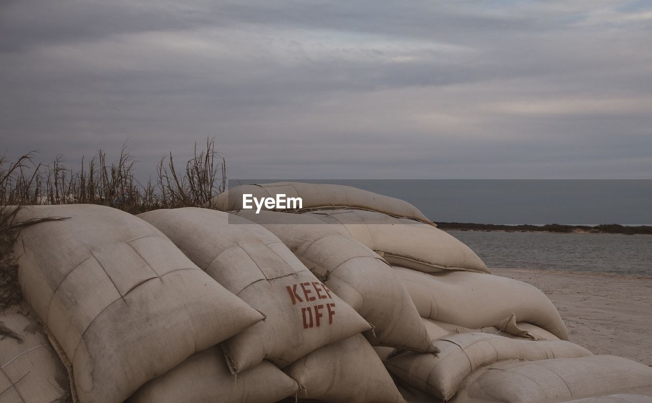 Sacks at beach against cloudy sky during sunset