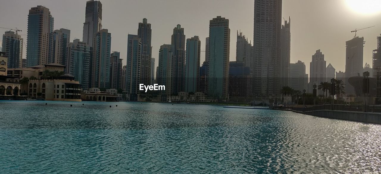 MODERN BUILDINGS BY SWIMMING POOL AGAINST SKY