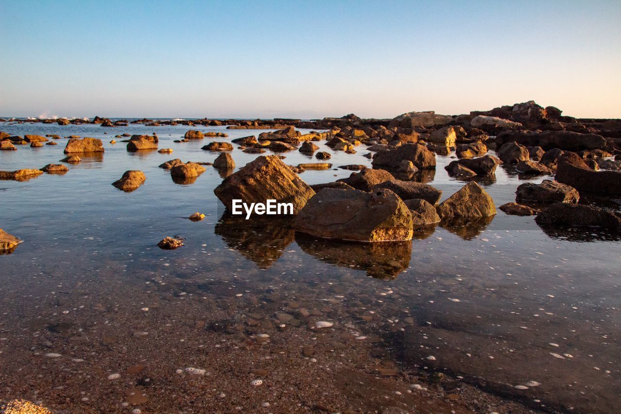 Rocks on beach against clear sky