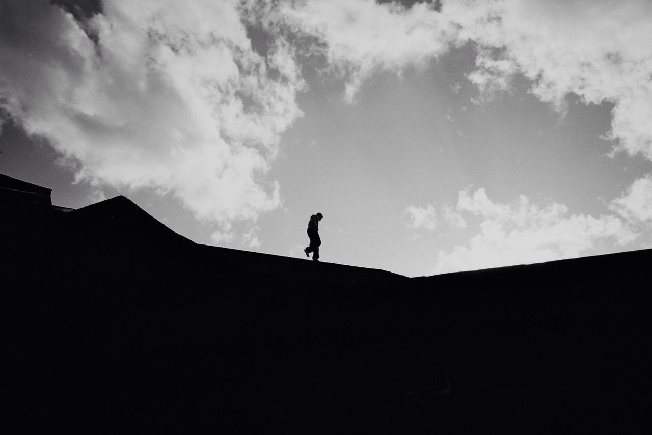 Silhouette man walking of roof against sky