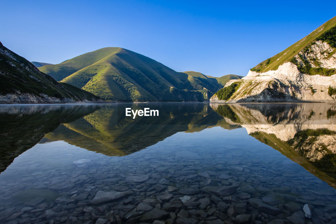 Lake kezenoy am in the green mountains. scenic view of lake and mountains against clear blue sky