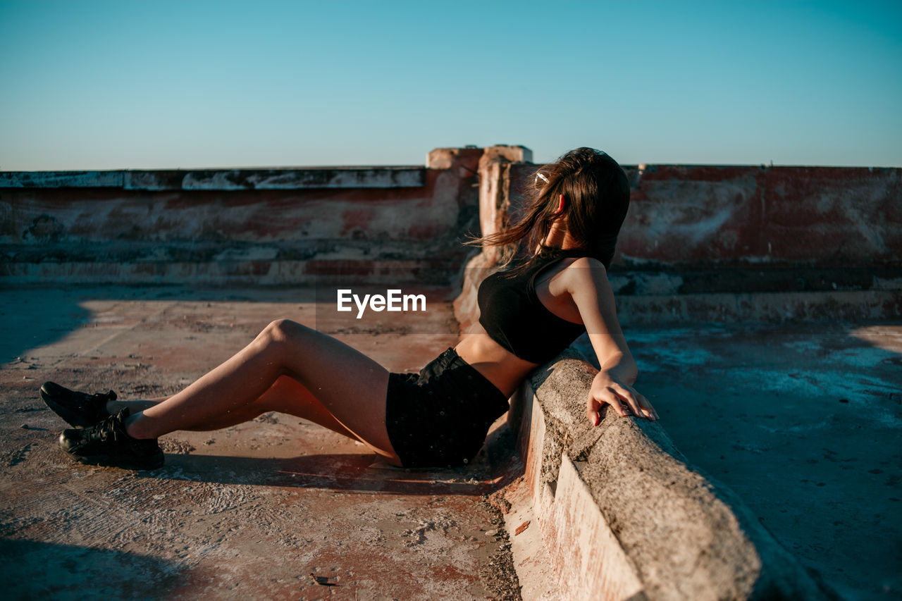 Young woman on terrace against clear sky