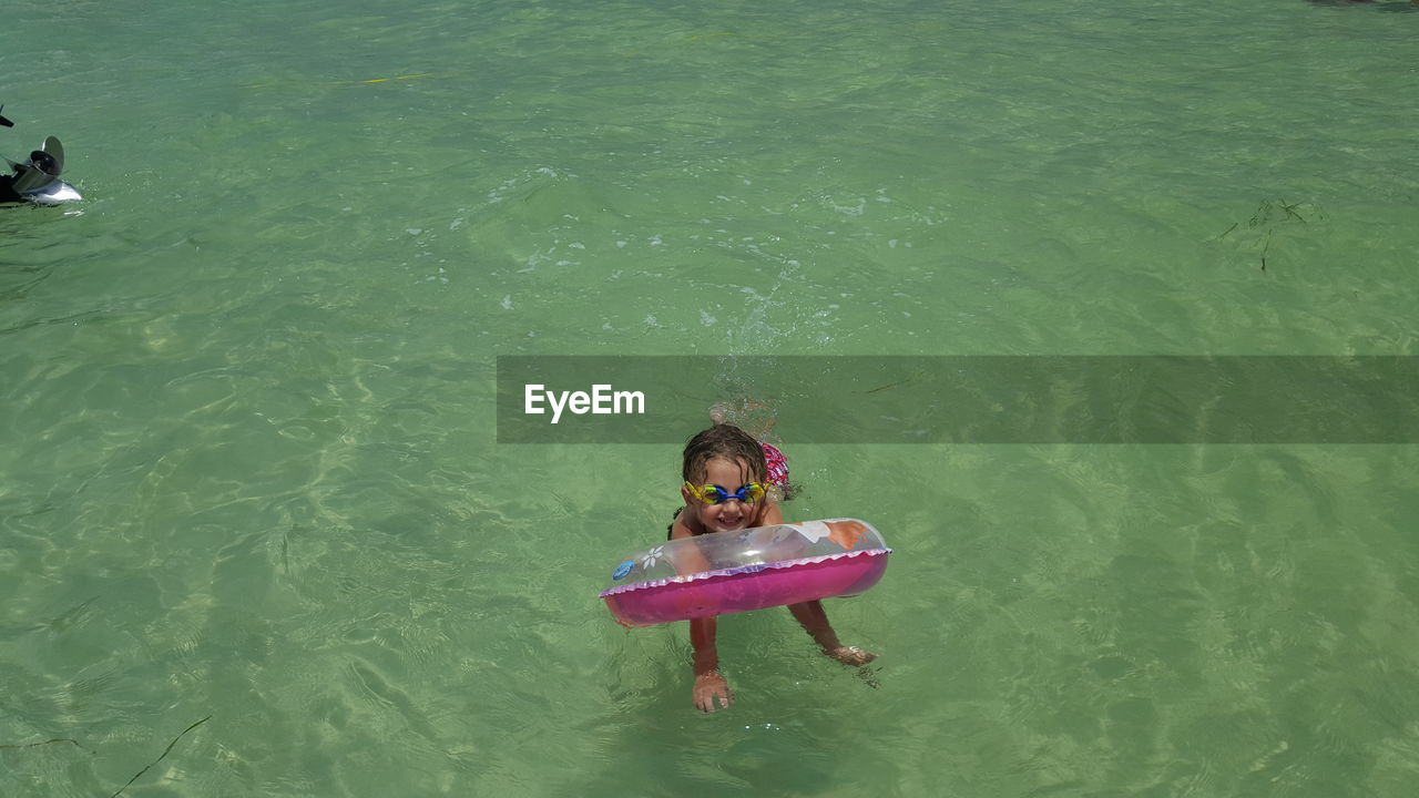 High angle view of little girl with inflatable ring swimming in sea
