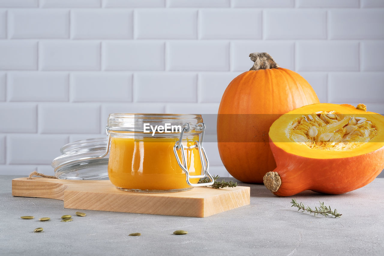 Pumpkin puree soup with pumpkin seeds and thyme in glass jar on wooden kitchen board. ripe pumpkin. 