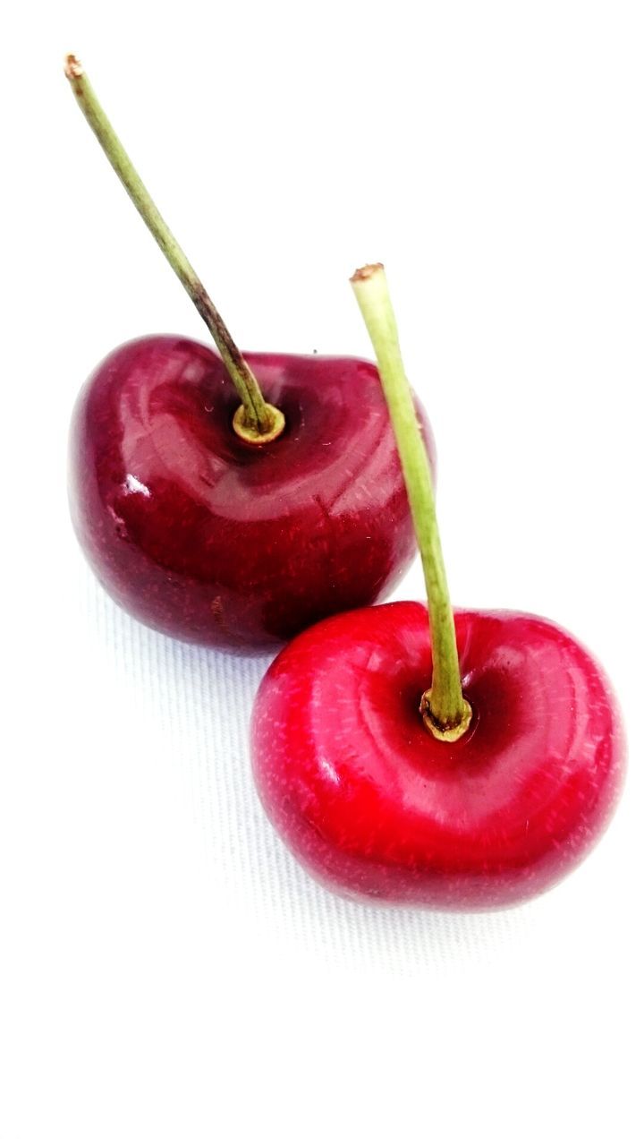 CLOSE-UP OF RED FRUIT OVER WHITE BACKGROUND