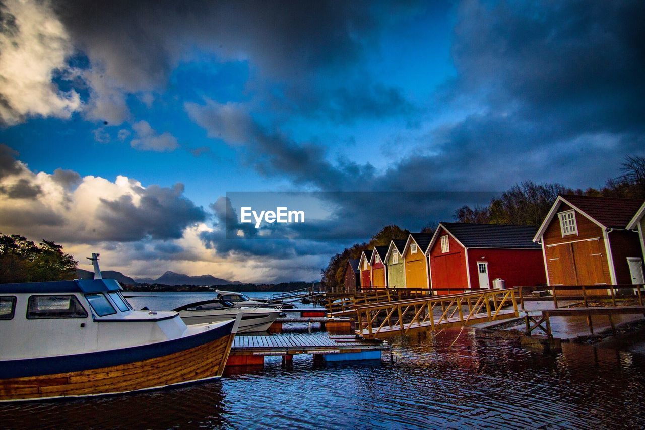 Boats moored on sea by houses against sky