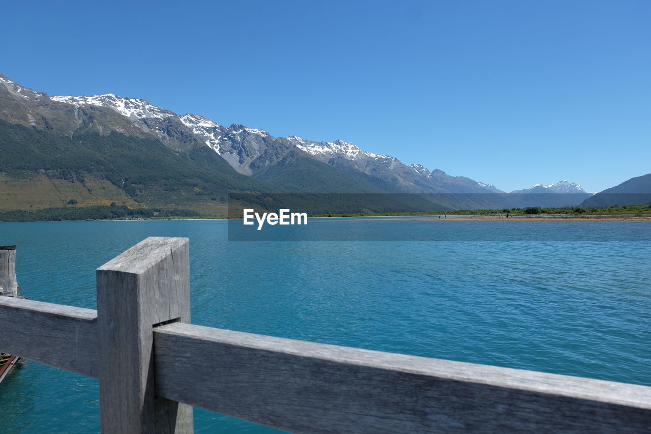 Scenic view of lake and mountains against clear blue sky