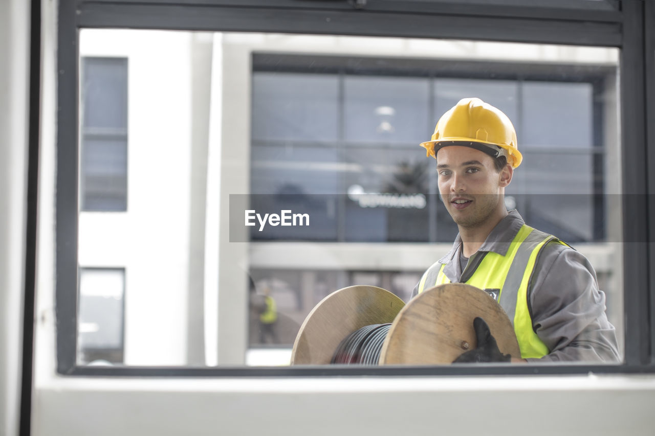 Portrait of construction worker carrying cable drum