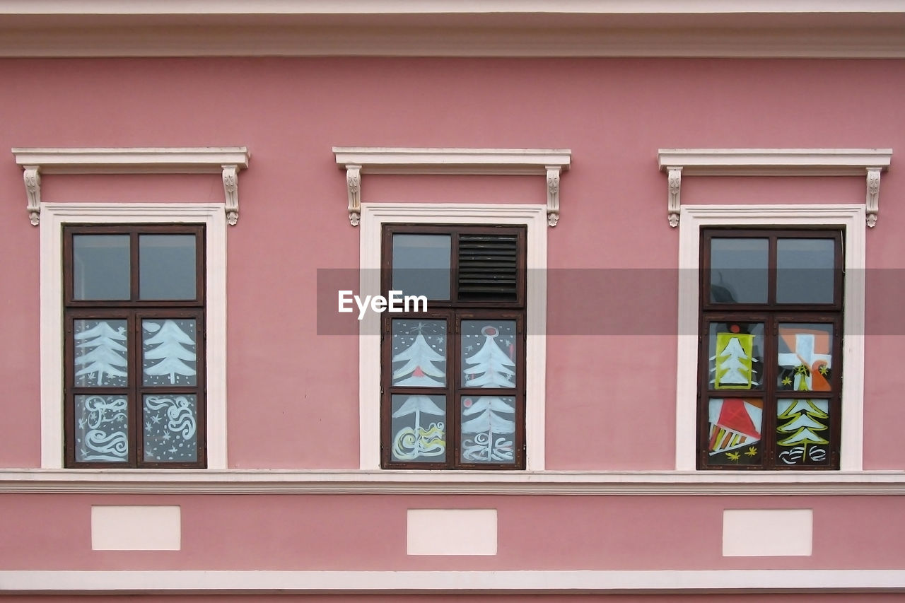 Three windows with christmas painting decoration on the pink wall
