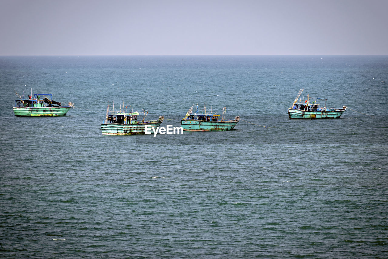 Small green fishing boats in the sea in rameswaram, india.