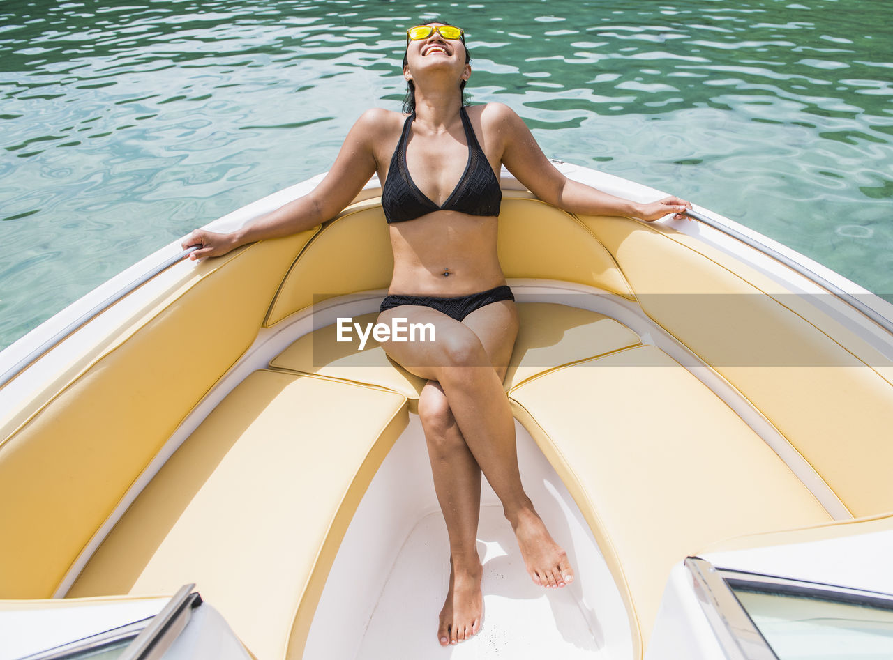 Woman sunbathing at the bow of a motor boat at a tropical island