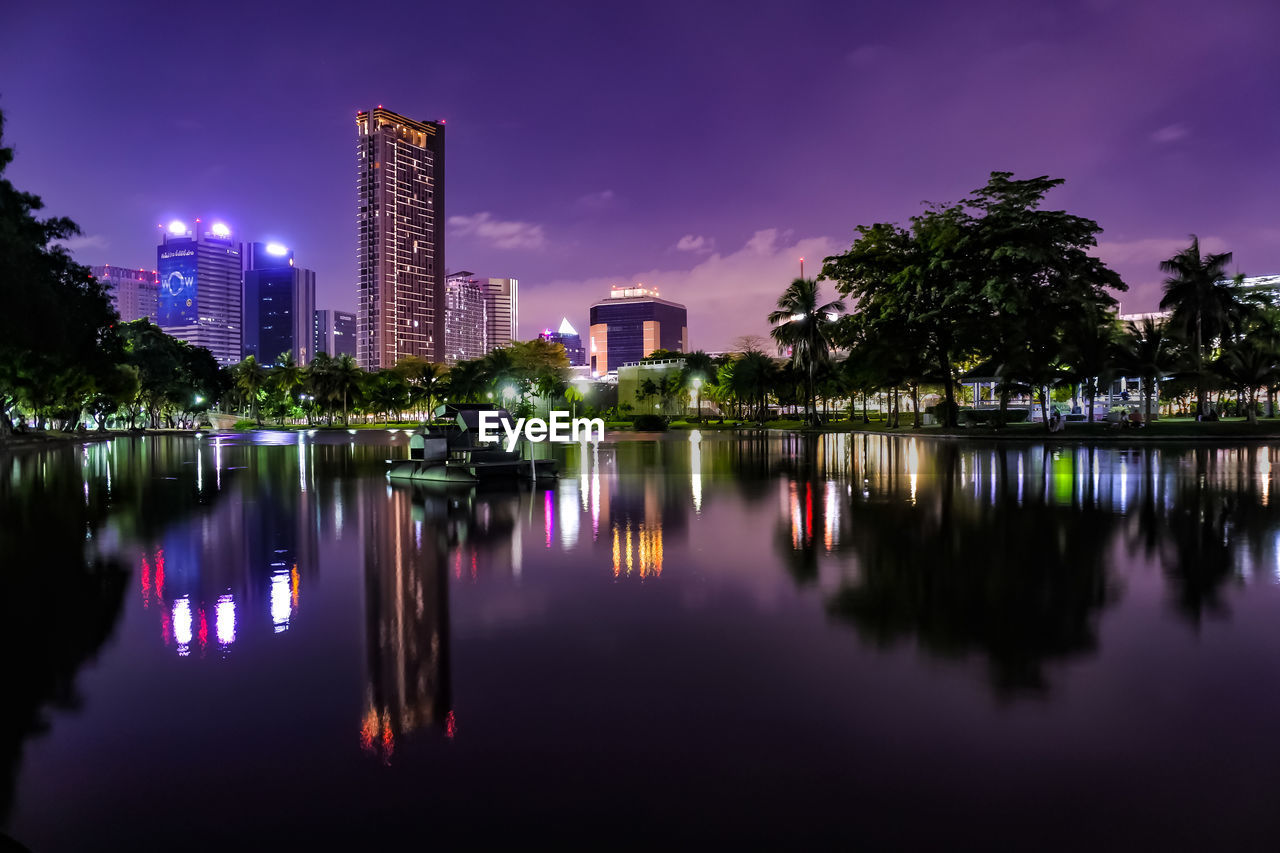 SCENIC VIEW OF LAKE AGAINST ILLUMINATED BUILDINGS AT DUSK