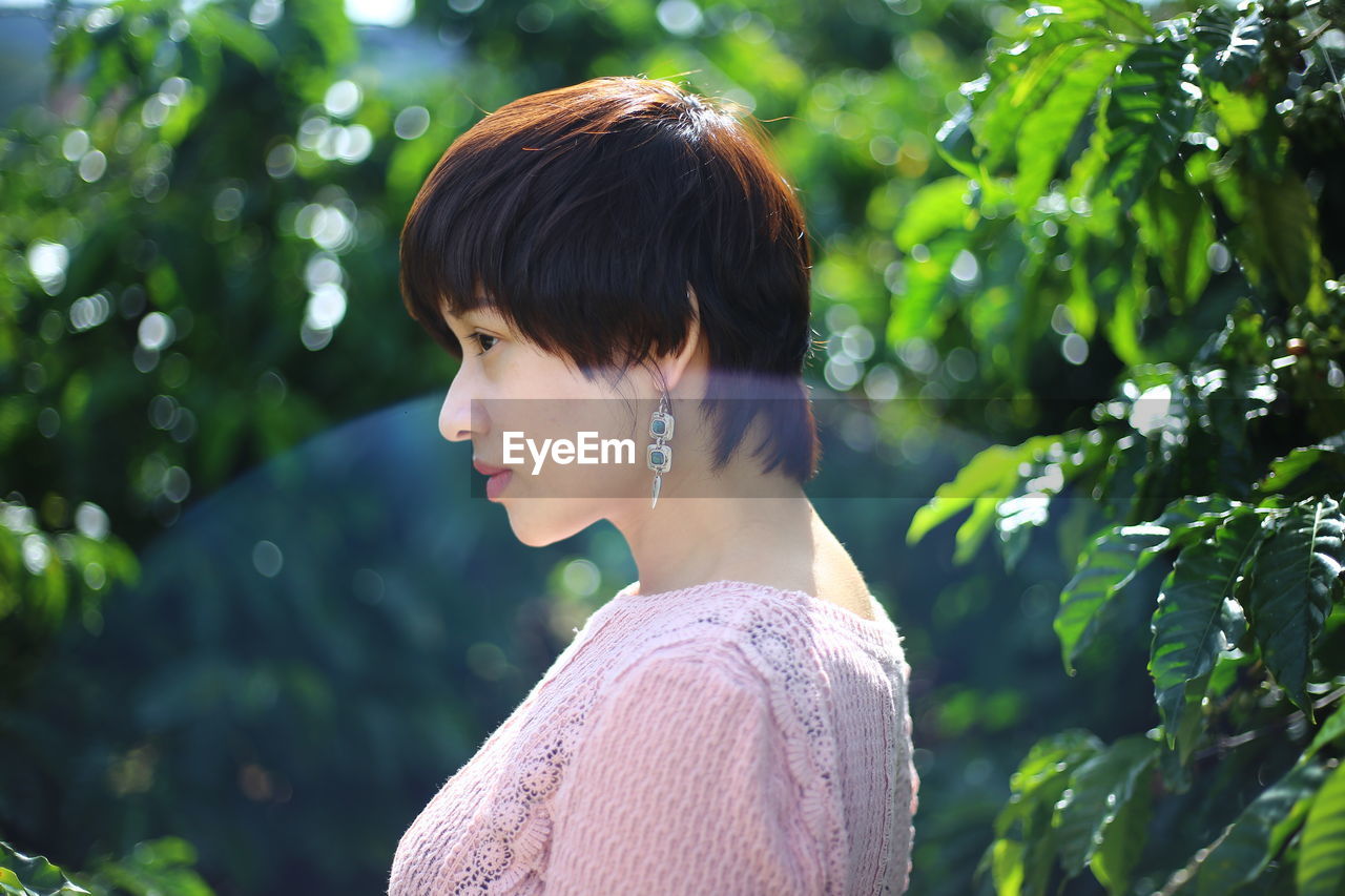 Side view of young woman by plants