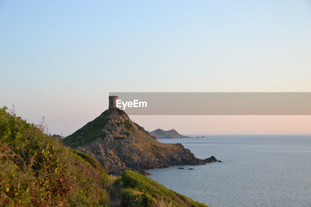 Scenic view of tower and sea against clear sky