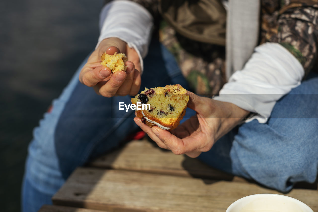 Eating cake by the lake...selective focus on hands. close up