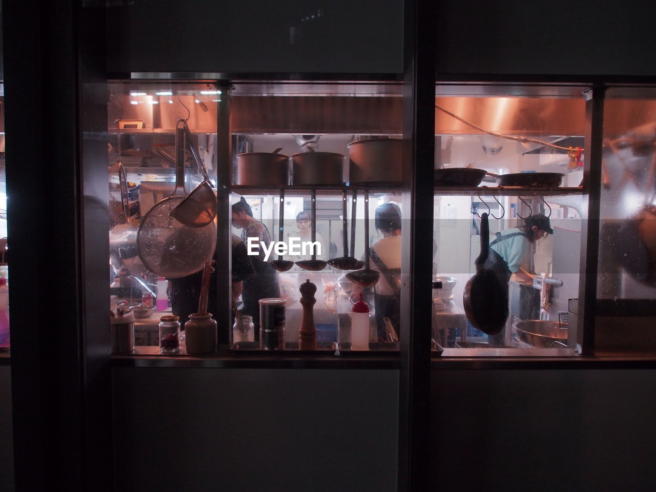 People working at restaurant kitchen through glass