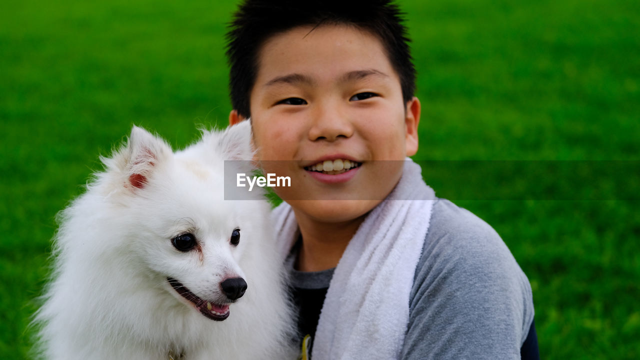 Close-up of smiling cute boy embracing dog