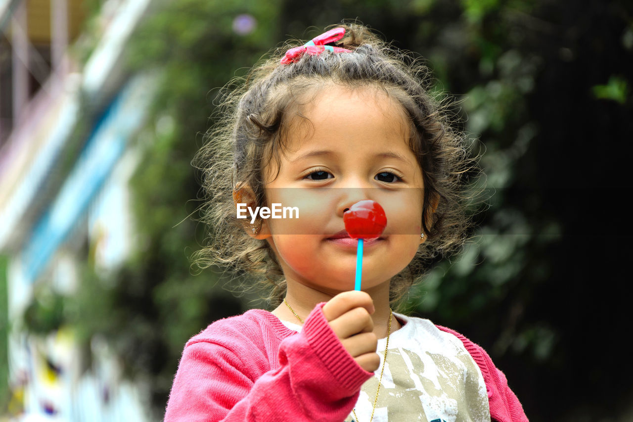 Portrait of cute girl holding lollipop outdoors