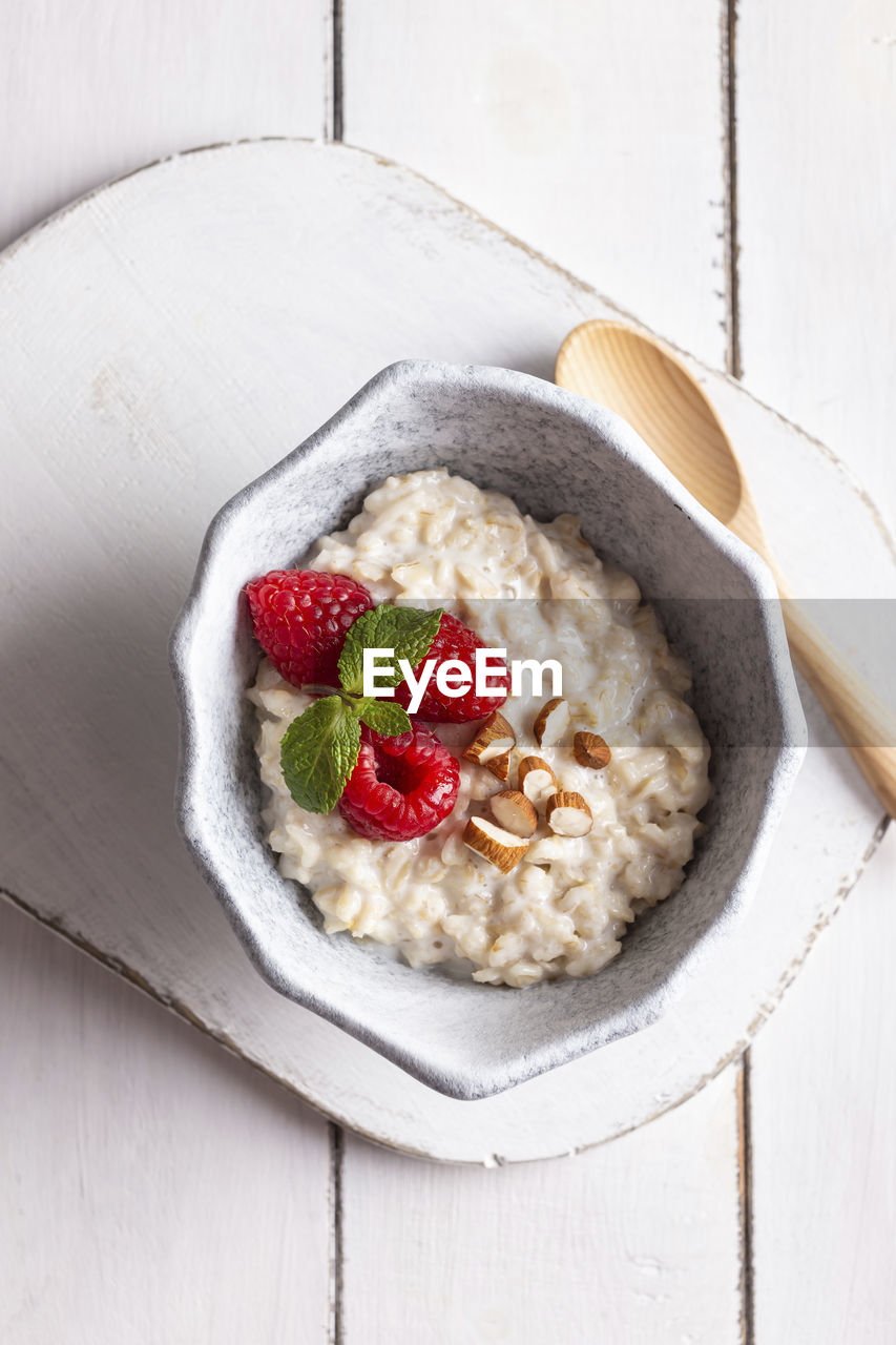 Bowl with cereal porridge decorated with raspberries and mint