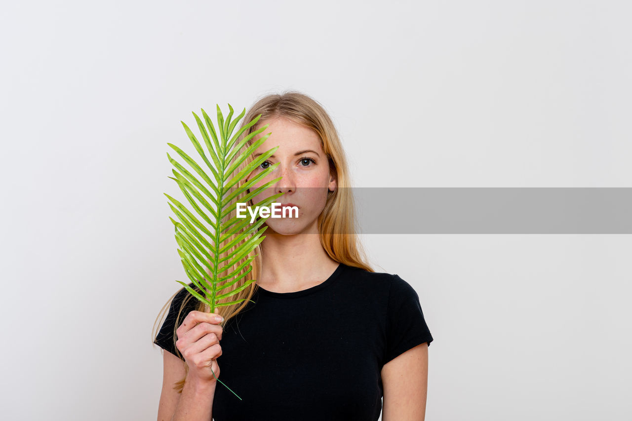 PORTRAIT OF YOUNG WOMAN HOLDING PLANT