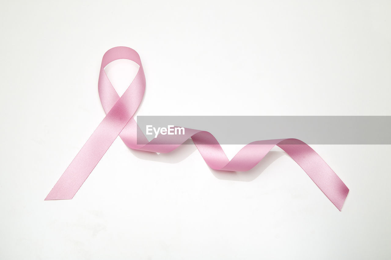 Close-up of pink ribbon on white background