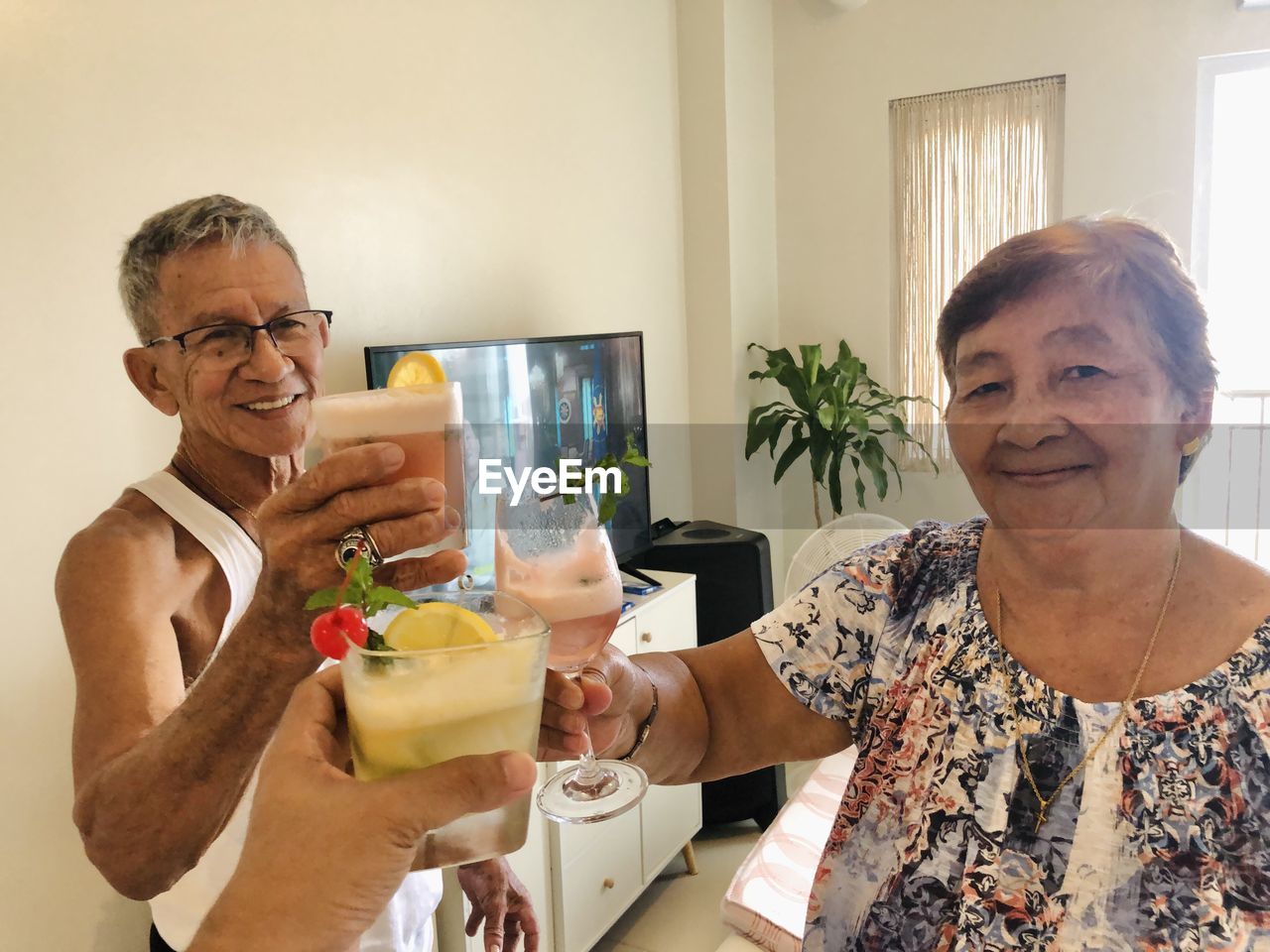 Portrait of old man and woman happily drinking at home