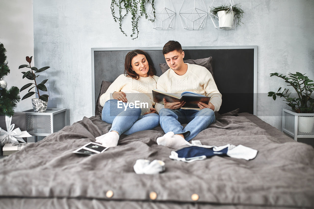 FULL LENGTH OF YOUNG COUPLE SITTING ON SOFA