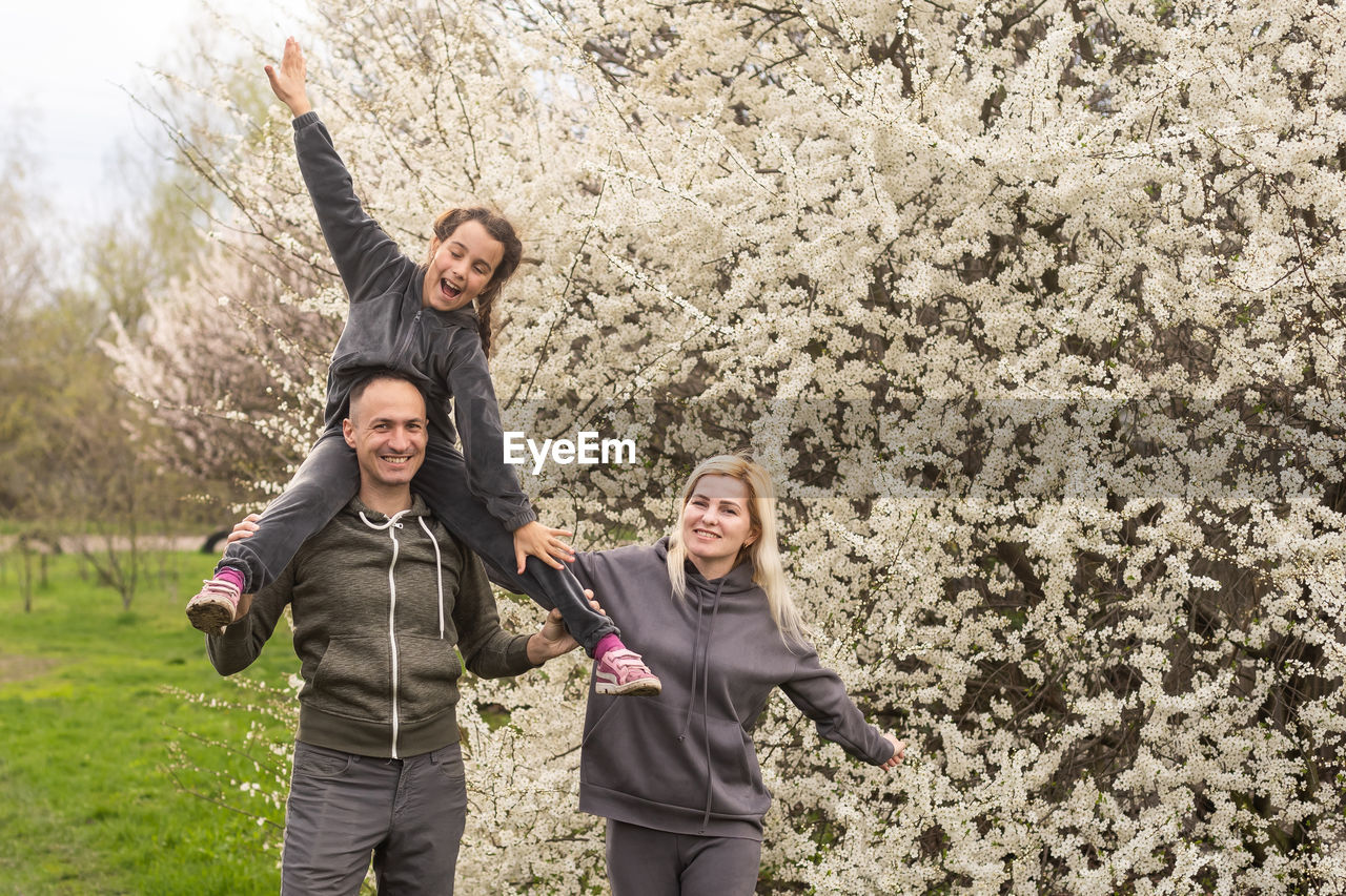 Family having fun with flowering tree in blooming spring garden