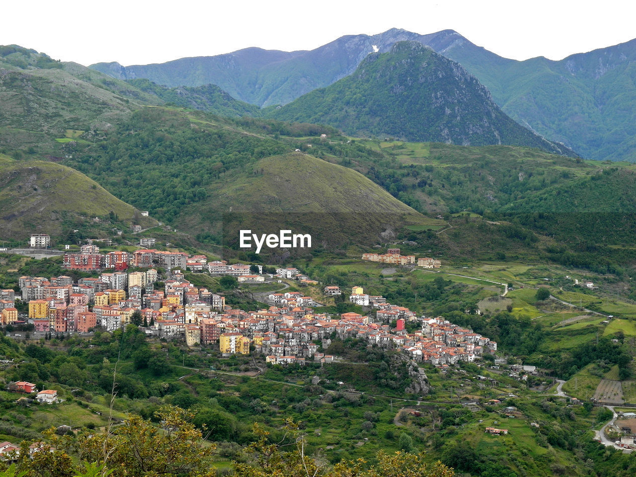 HIGH ANGLE VIEW OF HOUSES AND TREES AGAINST MOUNTAINS