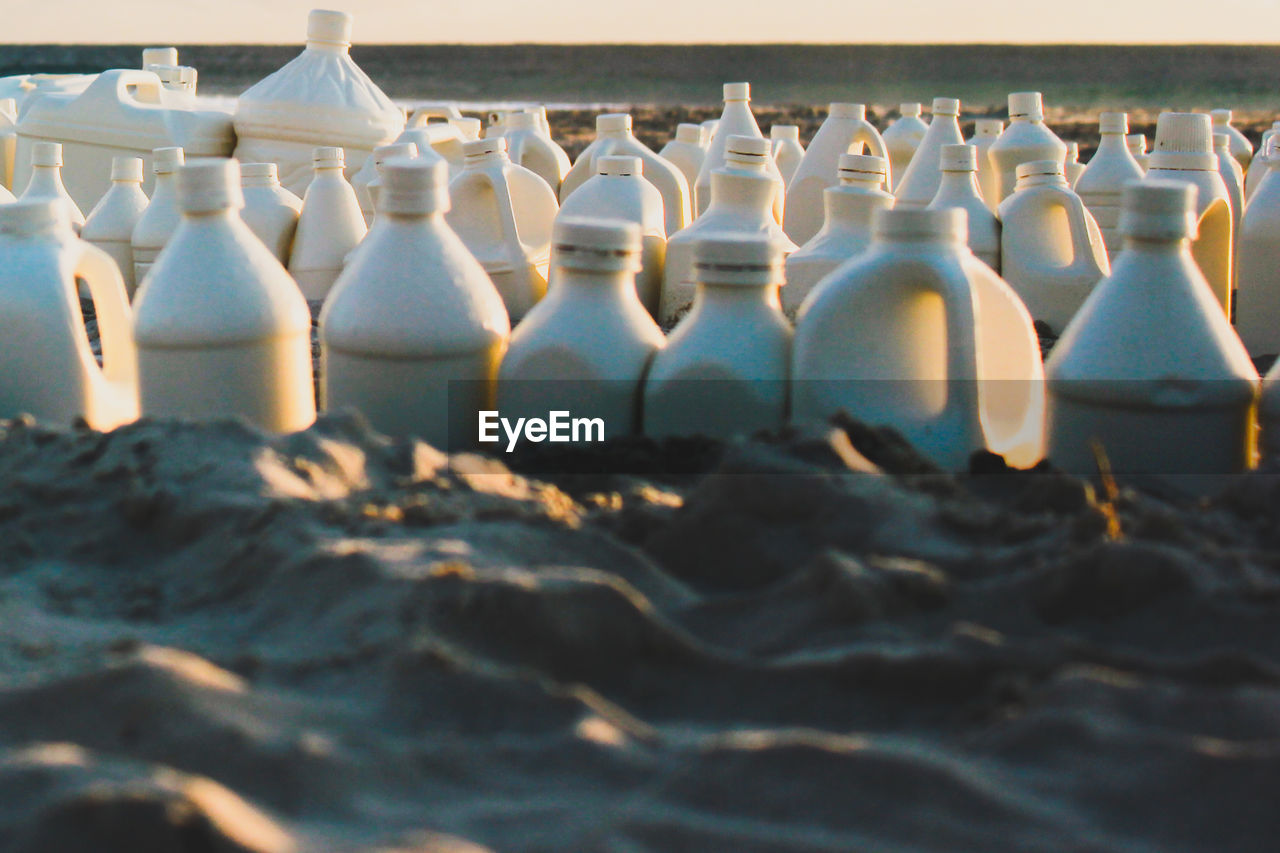 Close-up of bottles on sand at beach during sunset
