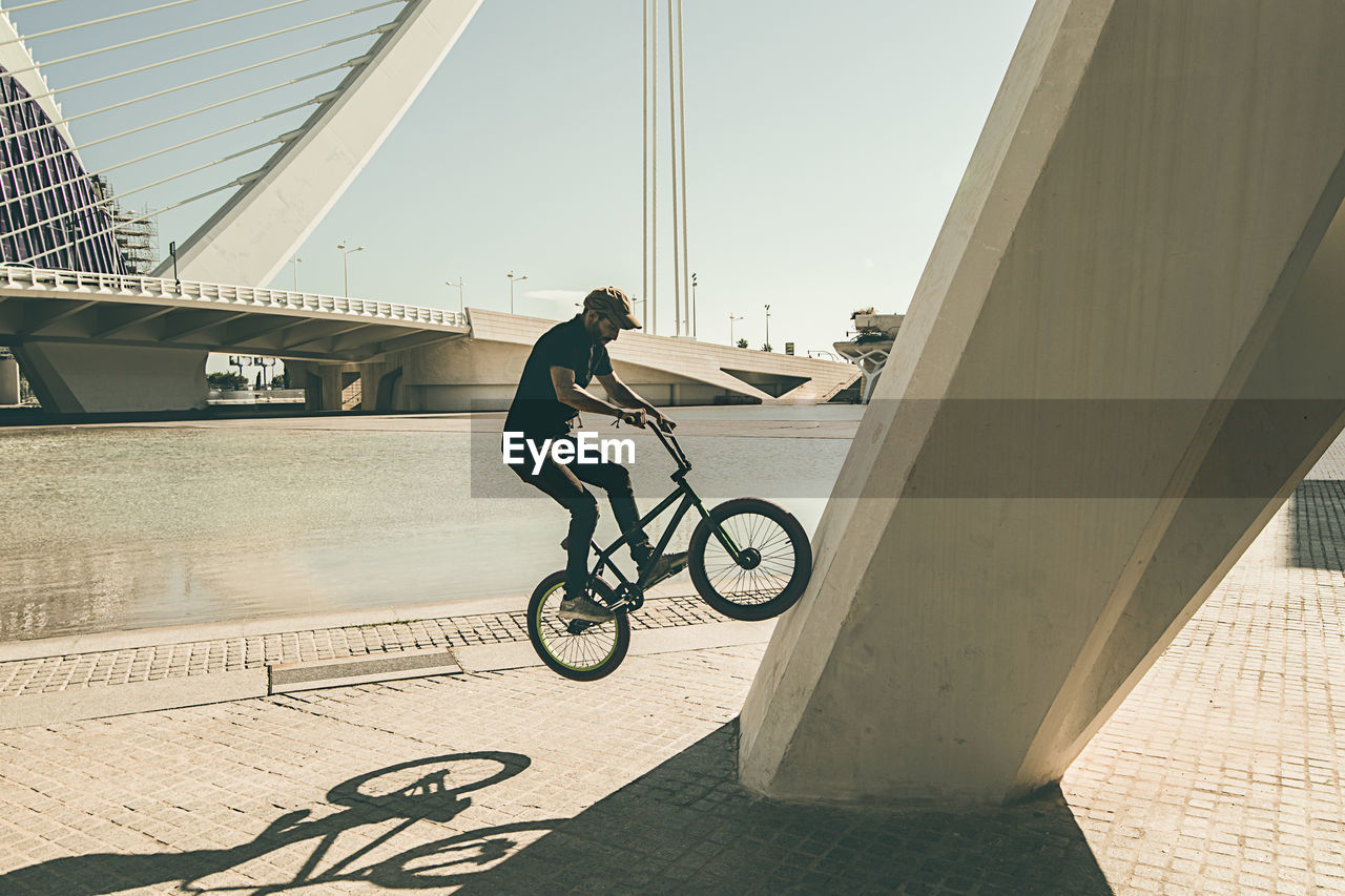 Man riding bmx cycle on footpath in city