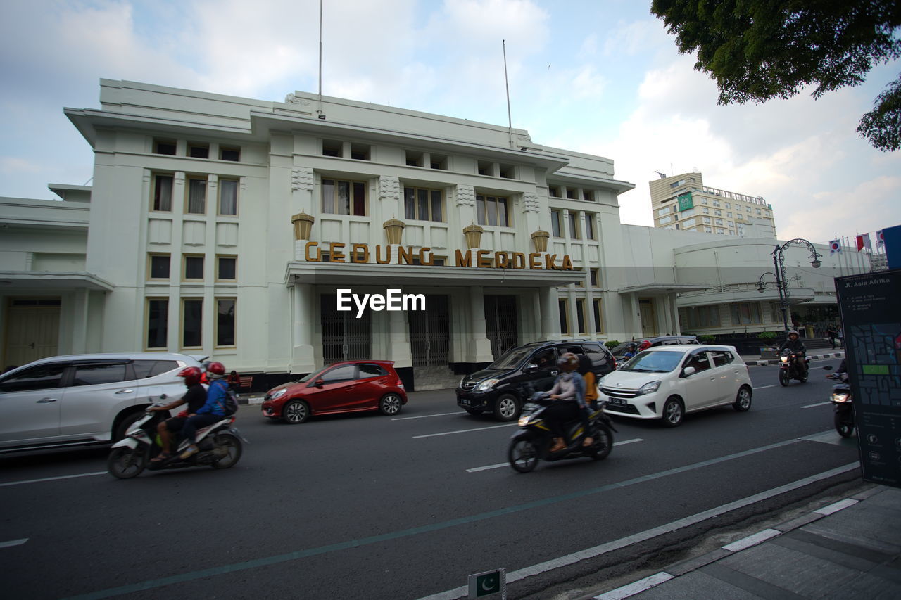 VEHICLES ON ROAD AGAINST BUILDINGS