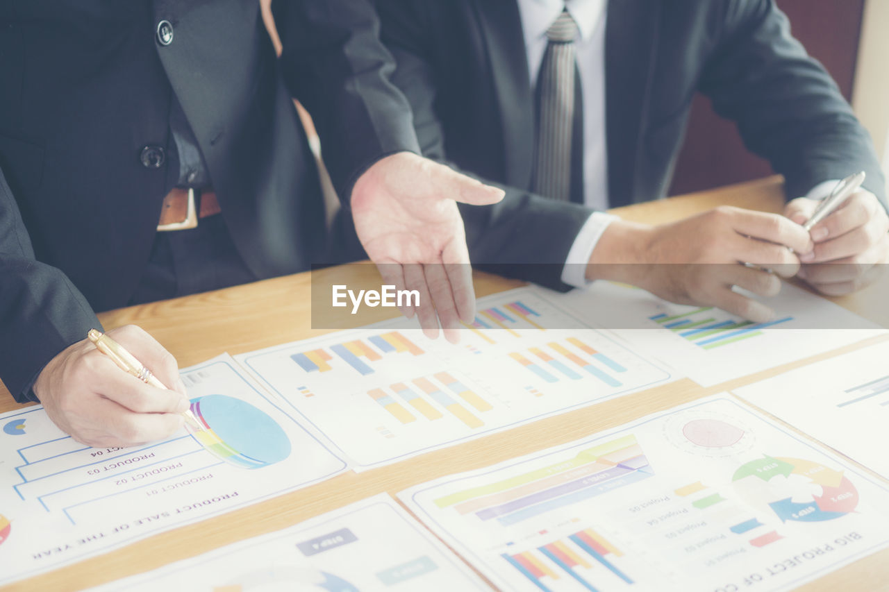 Close-up of businessman and colleague working over graph on table