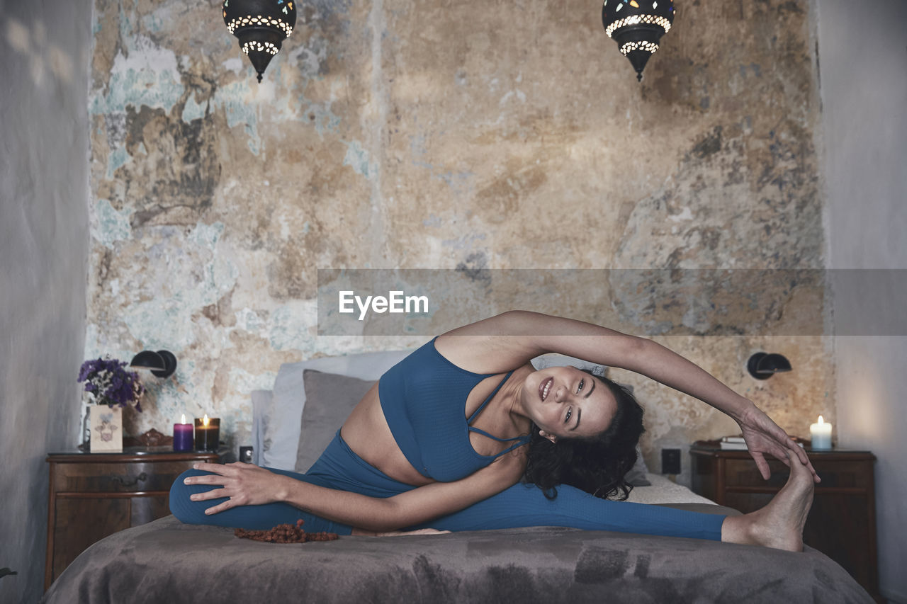 Woman exercising while sitting on bed at home