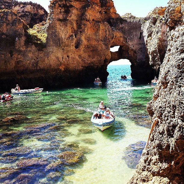 TOURISTS ON ROCK FORMATION IN SEA