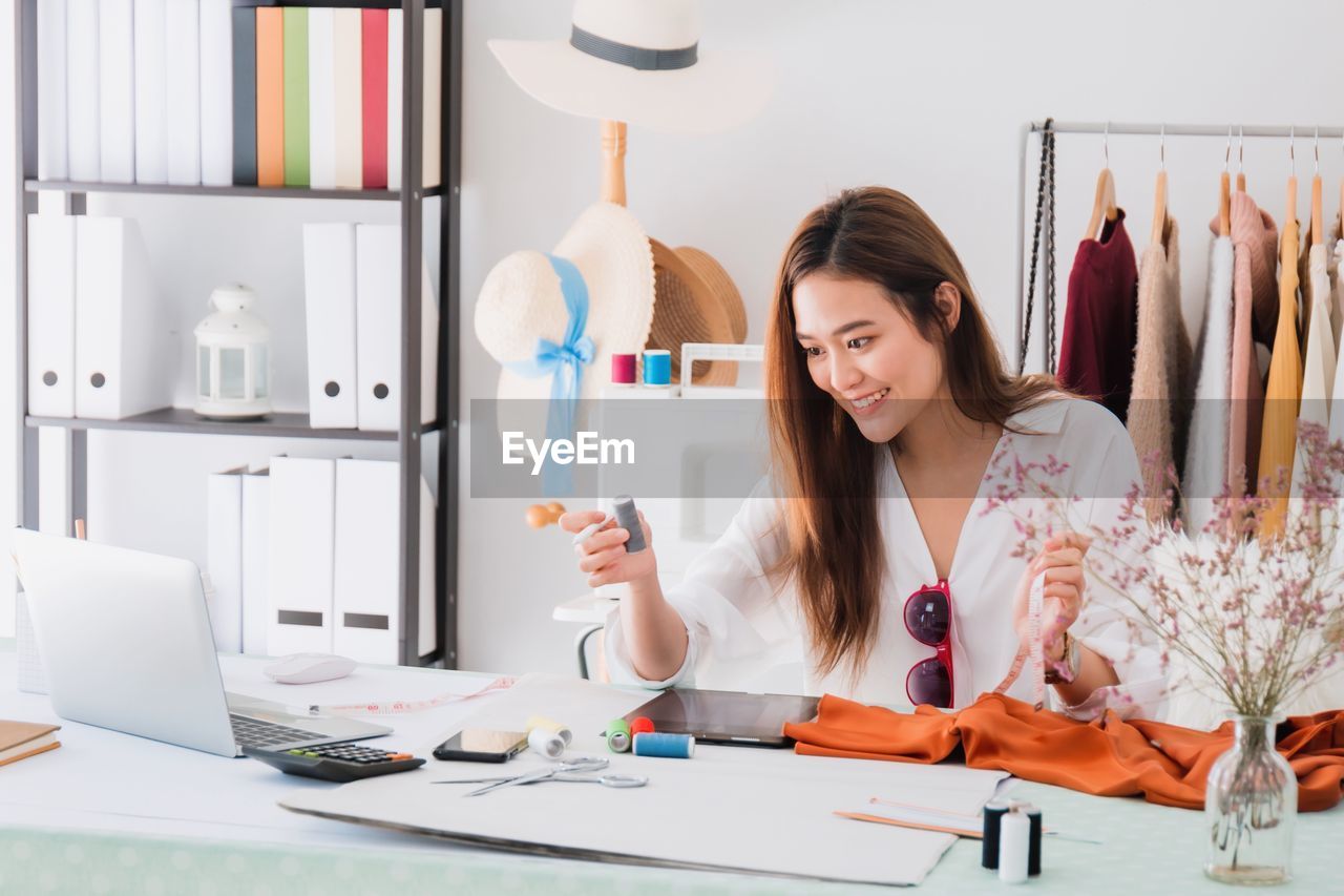 YOUNG WOMAN WORKING ON TABLE IN OFFICE