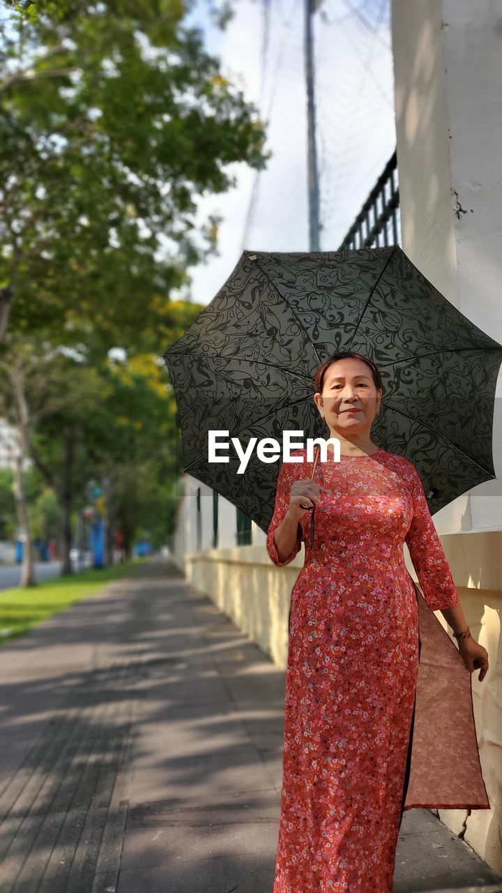 Portrait of smiling woman holding umbrella standing outdoors