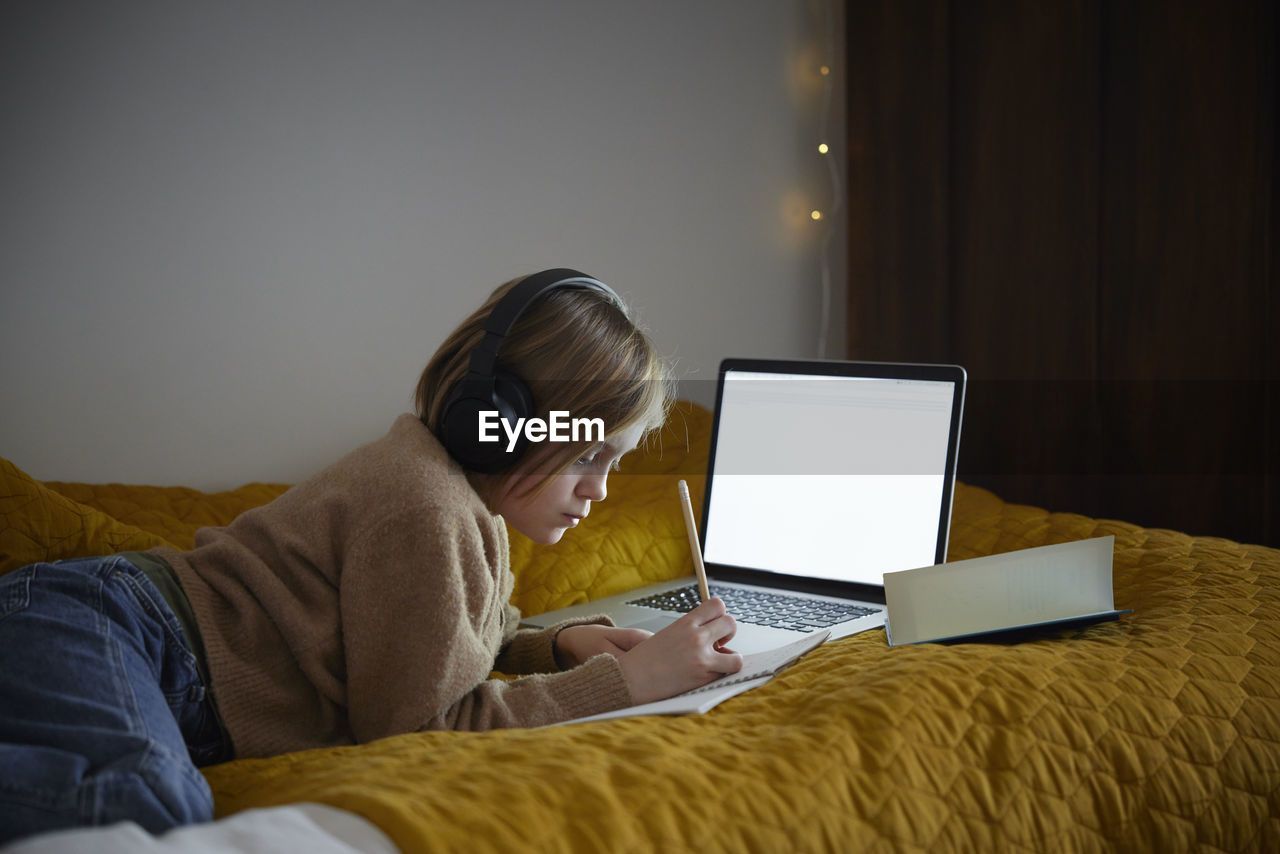 Girl doing homework with laptop in her bedroom