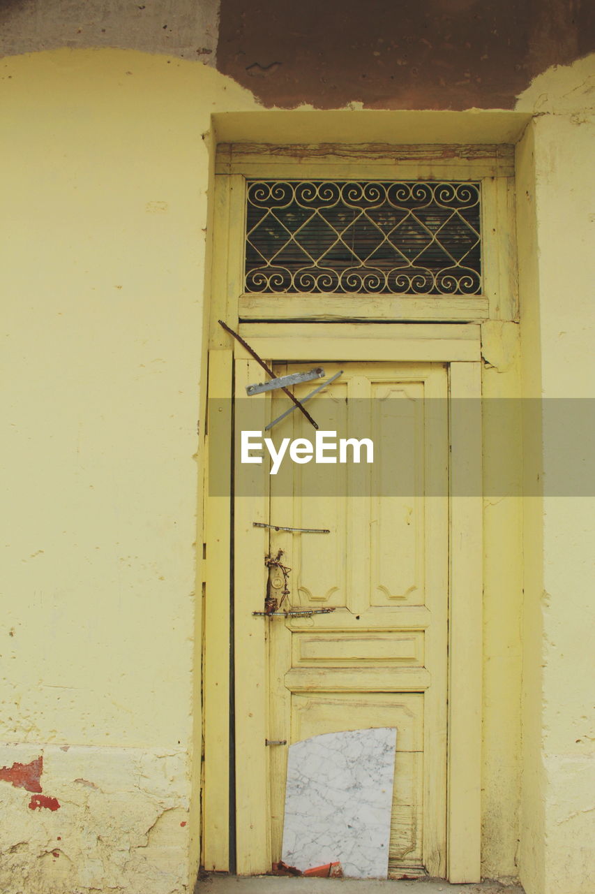 CLOSE-UP OF CLOSED DOOR WITH YELLOW BUILDING