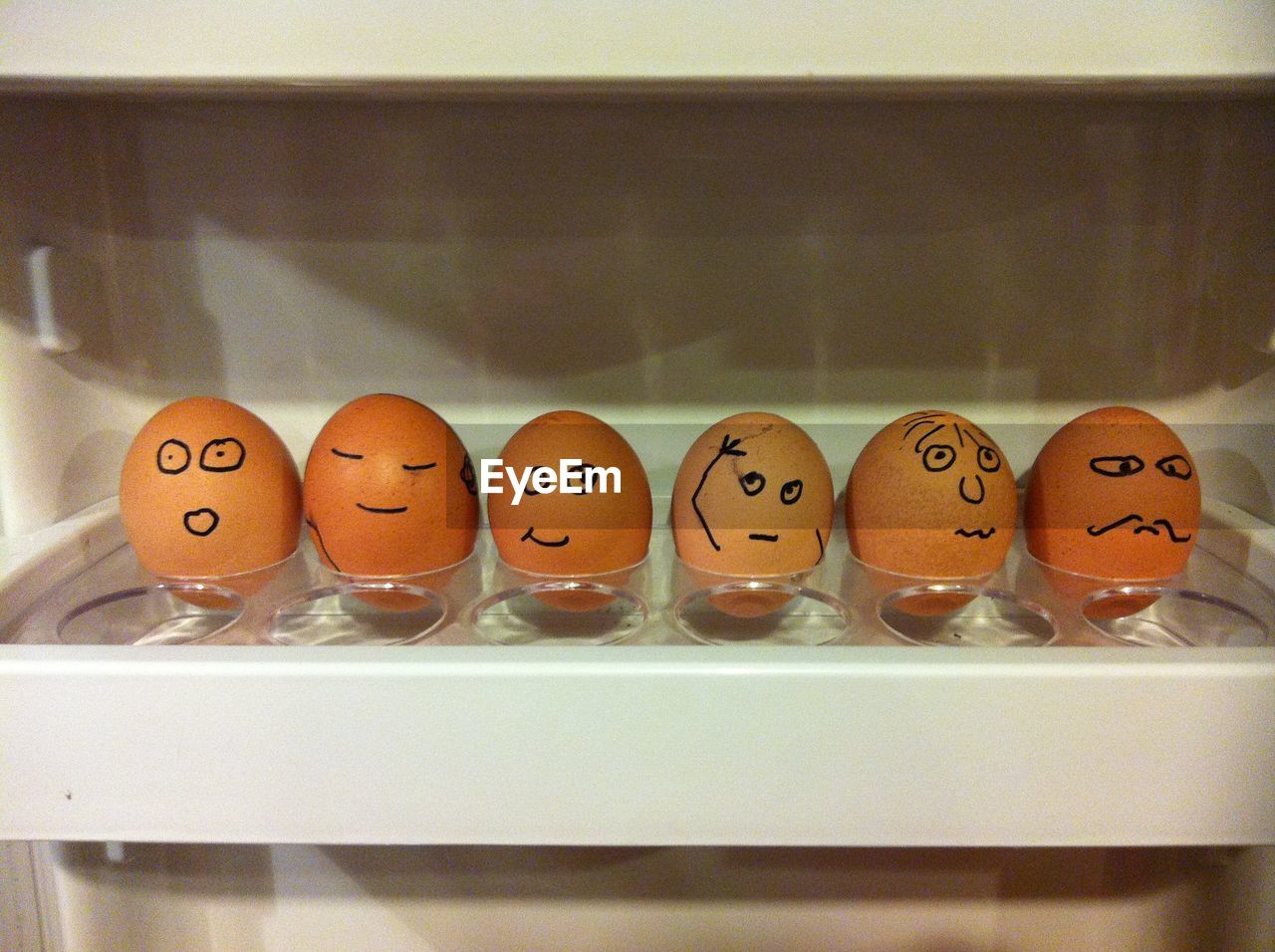 Close-up of anthropomorphic faces on eggs in carton