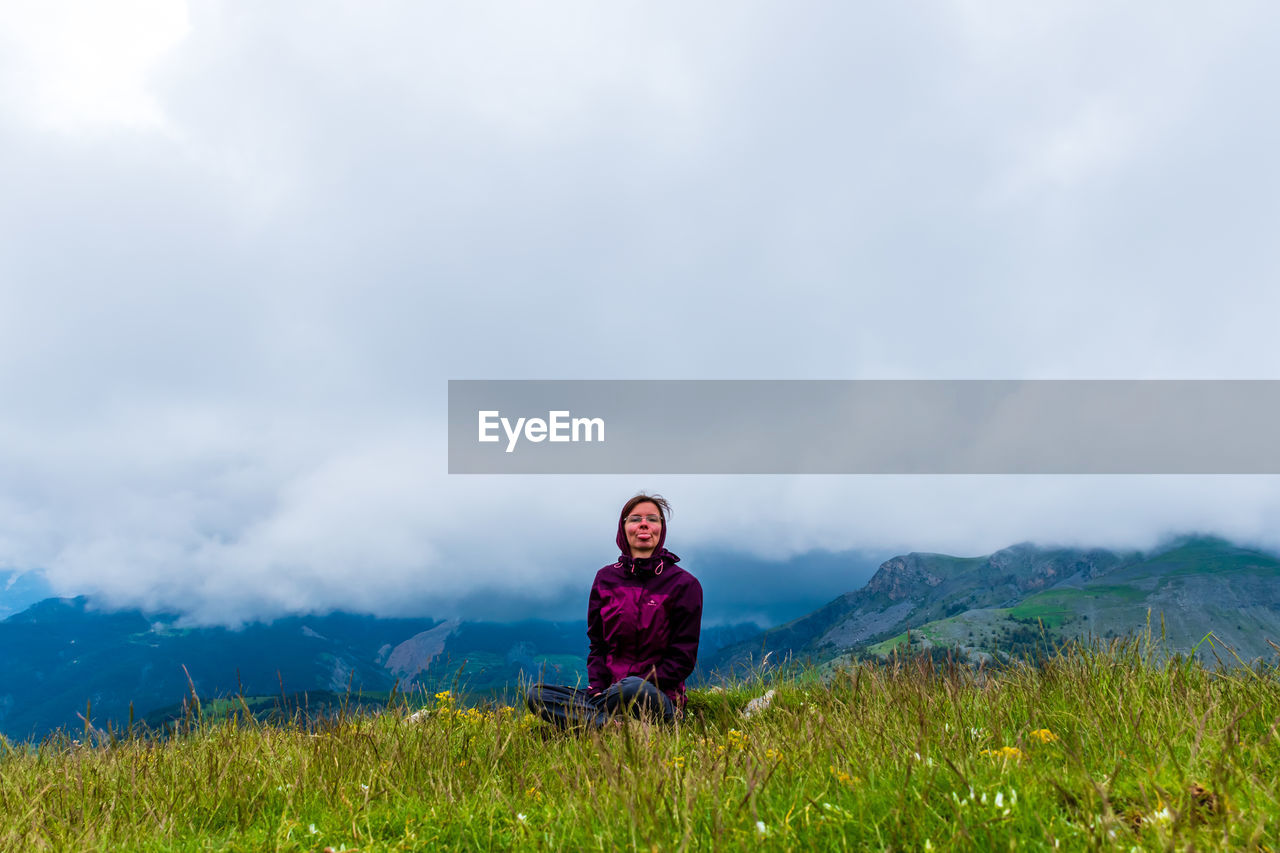 A young female hiker on a break during a hike on a cloudy summer day in the french alps