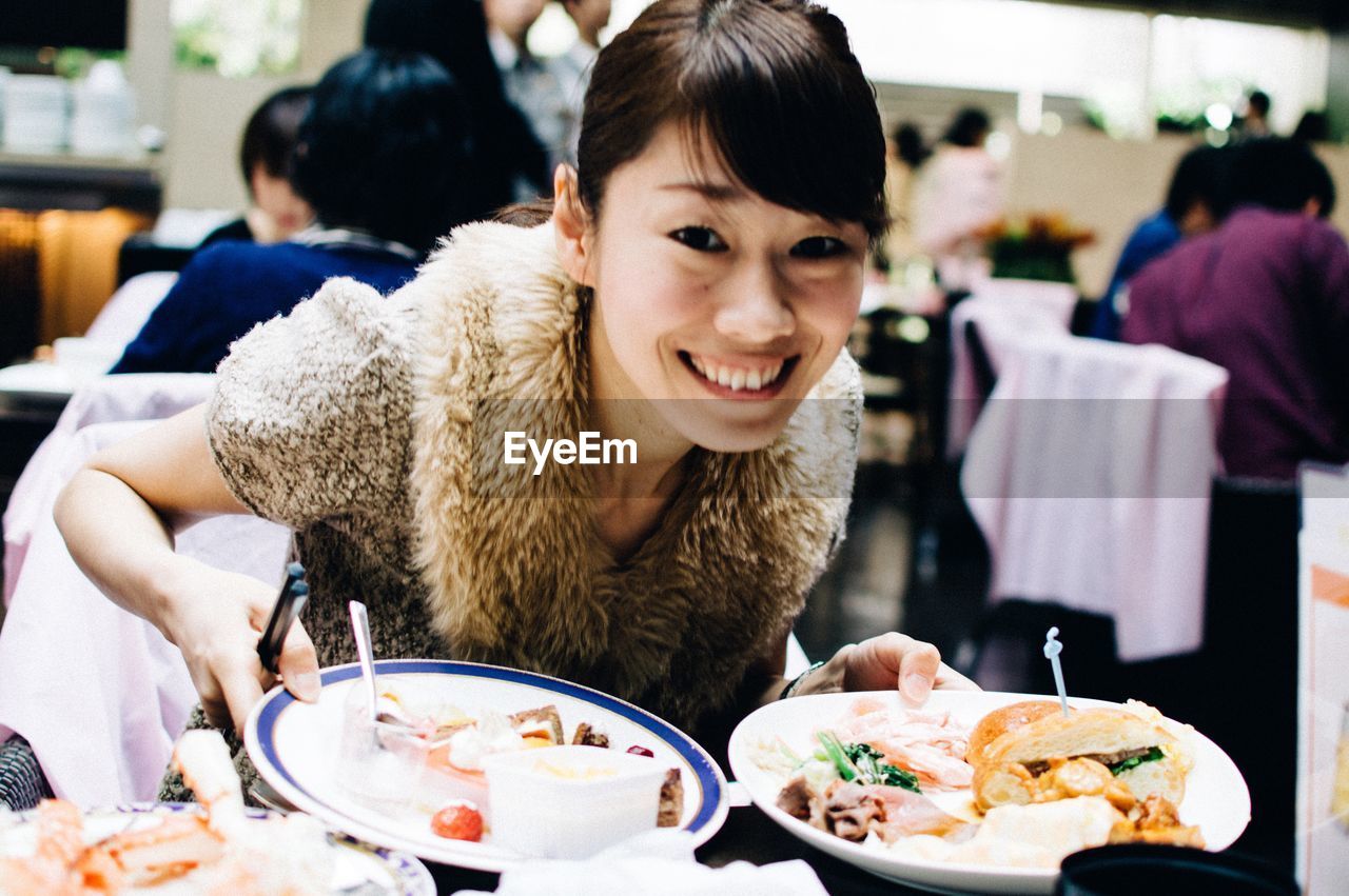 PORTRAIT OF YOUNG WOMAN SITTING ON RESTAURANT