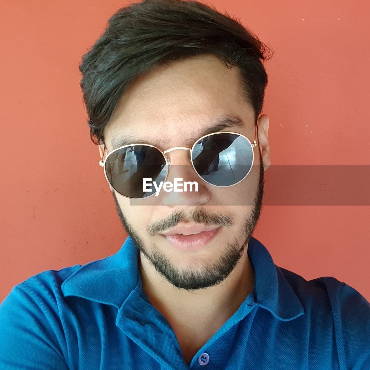 Portrait of young man wearing sunglasses against red background